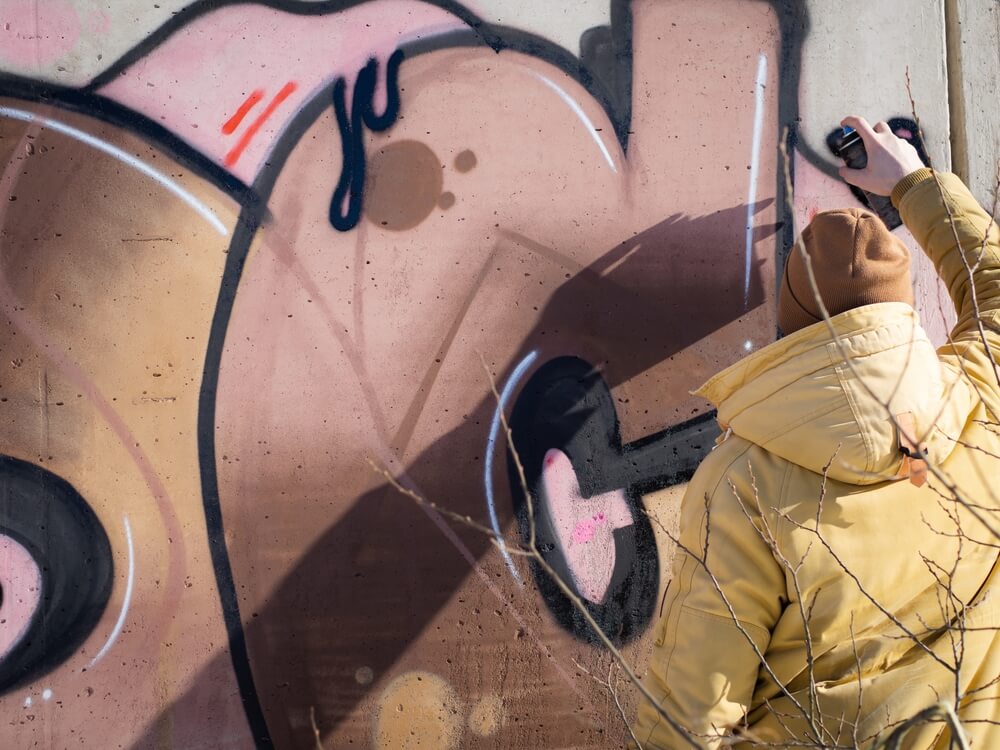 mężczyzna w kurtce malujący grafitti